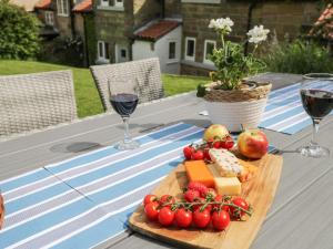 a table with cheese and tomatoes and glasses of wine at 1 Belle Vue in Osmotherley