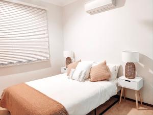 1 dormitorio blanco con 1 cama y 2 lámparas en Carnarvon 3BR & 2BA Holiday House en Carnarvon