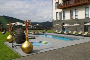 a pool with gold vases and chairs next to a building at Radisson Blu Resort Bukovel in Bukovel