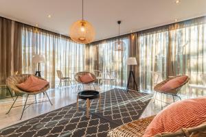 a living room with chairs and tables and windows at Topazio Vibe Beach Hotel & Apartments - Adults Friendly in Albufeira