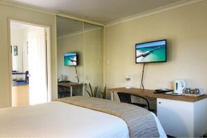 
a hotel room with two beds and a television at Observatory Guesthouse - Adults Only in Busselton
