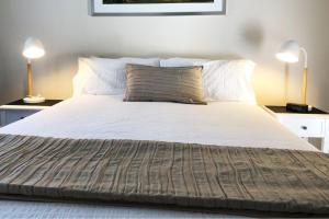 
a bed with a white comforter and pillows at Observatory Guesthouse - Adults Only in Busselton

