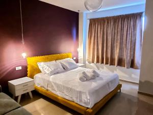 a bedroom with a bed with a yellow headboard and a window at Epipleon Luxury Suites - 107 - Διαμέρισμα 85τμ - Θέα στη θάλασσα in Nafpaktos