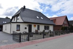 ein weißes Haus mit schwarzem Dach hinter einem Zaun in der Unterkunft Karlshagen - Lissis Feriendomizil in Ostseebad Karlshagen