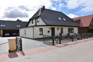 ein weißes Gebäude mit einem schwarzen Dach auf einer Straße in der Unterkunft Karlshagen - Lissis Feriendomizil in Ostseebad Karlshagen
