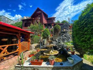 a house with a garden with a fountain and potted plants at Pensiunea El Plazza in Băile Herculane