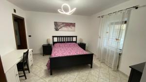 1 dormitorio con 1 cama con colcha rosa en La Ciuenda en Perosa Argentina