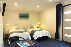 a hotel room with two beds and a table with a table sidx sidx at Observatory Guesthouse - Adults Only in Busselton