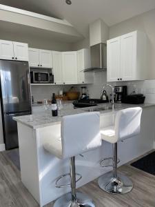 a kitchen with white cabinets and white bar stools at Port Renfrew Oceanfront Retreat in Port Renfrew