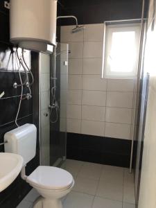 a bathroom with a toilet and a shower and a window at Guesthouse Adriatic in Biograd na Moru
