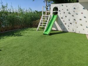 a green slide with a ladder next to a climbing wall at Apartments Relax in Dunajská Streda