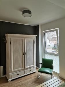 a room with a cabinet and a green chair at Sonnenufer Apartment & Moselwein I in Bernkastel-Kues