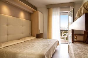 a bedroom with two beds and a large window at Hotel Torino in Lido di Jesolo