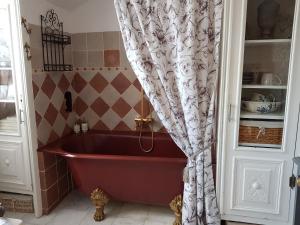 eine rote Badewanne im Bad mit einem Duschvorhang in der Unterkunft La Marlottine in Bourron-Marlotte
