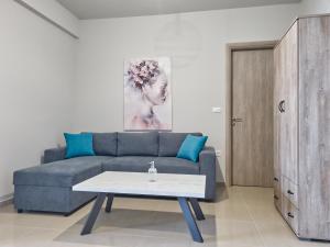 een woonkamer met een blauwe bank en een tafel bij Epipleon Luxury Suites -106- Δωμάτιο 40τμ με βεράντα 45τμ μπροστά στην θάλασσα in Nafpaktos