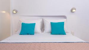 a bed with white pillows and blue pillows at Seaside Breeze in Kamari
