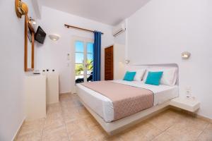 a white bedroom with a bed and a balcony at Seaside Breeze in Kamari
