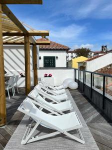 a row of white lounge chairs on a balcony at PDL Green House in Ponta Delgada