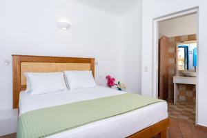 a bedroom with a white bed with a green blanket at Seaside Breeze in Kamari