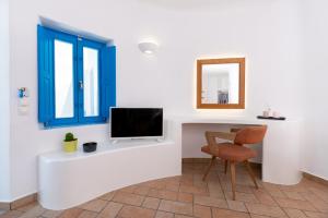 a room with a tv and a chair and a mirror at Seaside Breeze in Kamari