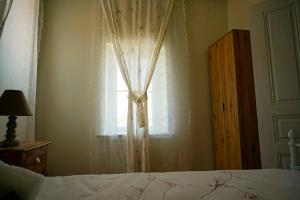 a bedroom with a bed and a window with curtains at Charikleia's country house in Pelion in Volos