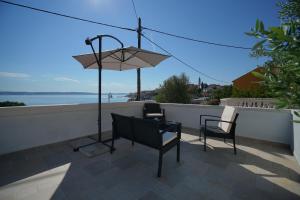 a patio with two chairs and a table and an umbrella at Angelina - stone house in Kali