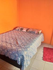 Acomodaçaoes koynonya في سيت لاغواس: سرير في غرفة بجدار برتقالي