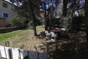 a picnic table and chairs in a yard with a fence at Location Rez de maison dans quartier charmant in Saint-Raphaël