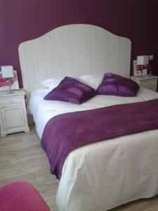 a bedroom with a large bed with purple pillows at Le Clos des Oiseaux in Saintes