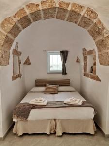 een slaapkamer met een bed in een witte kamer bij I Trulli dell'Orfanello in Martina Franca