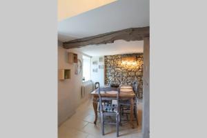 ein Esszimmer mit einem Tisch, Stühlen und einer Steinmauer in der Unterkunft Les chemins du Mont in Lortet