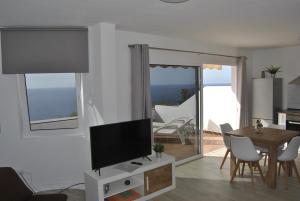 ein Wohnzimmer mit Fernseher und Tisch mit Stühlen in der Unterkunft Sunset La Palmita in La Victoria de Acentejo