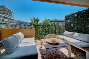 a patio with a couch and a table on a balcony at Elisa - Traversant - Terrasse - Verrière Côte d'Azur in Cannes