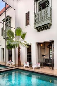 a villa with a swimming pool and a palm tree at Riad Antara in Marrakesh