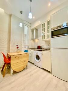 a kitchen with white cabinets and a table and a dishwasher at Charming Puerta del Sol Center in Madrid