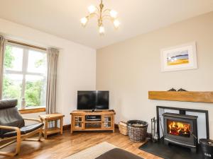 a living room with a fireplace and a television at 2 Swordale Cottages in Dingwall