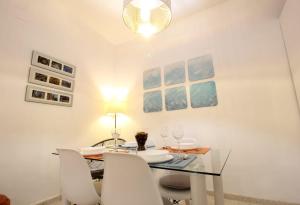 comedor con mesa de cristal y sillas blancas en Apartamento Pastora Sevilla, en Sevilla