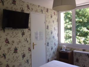 a bedroom with a bed and a television on the wall at Hotel Richelieu in Calais