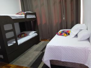 a bedroom with two bunk beds with white sheets at Ensolarado ao lado do shopping com garagem e Wifi in Teresópolis