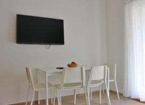 a dining room table with white chairs and a flat screen tv at Apartmani Bodo in Drvenik