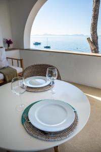 een witte tafel met twee borden en wijnglazen bij ALCUDIA-VIDA SANA-PRIMERA LINEA DE MAR in Alcudia