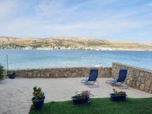 two blue chairs sitting on the sand near the water at Hrvoje in Pag