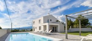 a white house with a swimming pool in front of it at NEW Villa Buterin with heated pool in Novigrad Dalmatia