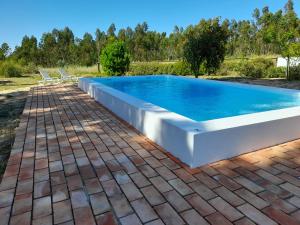 a large swimming pool with two chairs around it at Quintal Alentejano in Zambujeira do Mar