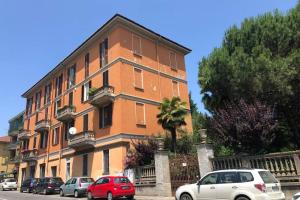 duży pomarańczowy budynek z samochodami zaparkowanymi przed nim w obiekcie Mazzini apartment w mieście Arona