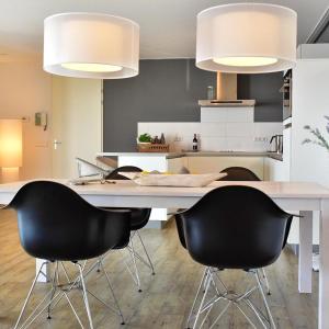 a kitchen with a large white table with black chairs at Näher am Wasser kann man nicht wohnen! in Arnemuiden