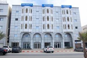 un bâtiment blanc avec des voitures garées devant lui dans l'établissement Valencia Hôtel & Appartements, à Nouadhibou