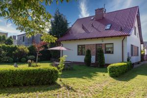 a white house with an umbrella in the yard at Willa Rybaczówka z ogrodem in Puck