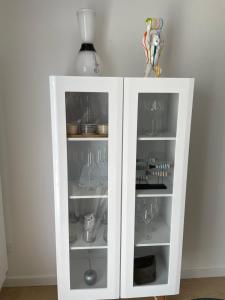 a white cabinet filled with dishes and wine glasses at Appartement T2 les minimes chic et cosy in La Rochelle