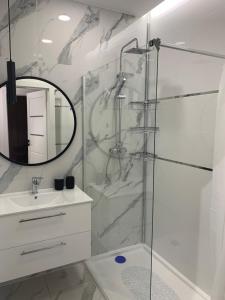 łazienka z prysznicem, umywalką i lustrem w obiekcie Apartament Joanna w mieście Giżycko